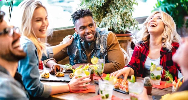 Friends laughing and drinking at table