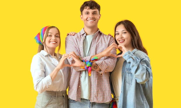 Three people standing together with heart hands yellow background