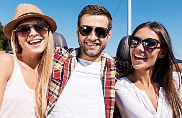 Man laughing with two women wearing sunglasses Man laughing with two women wearing sunglasses