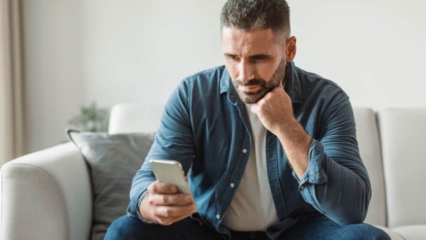 Mature man looking distressed on cellphone