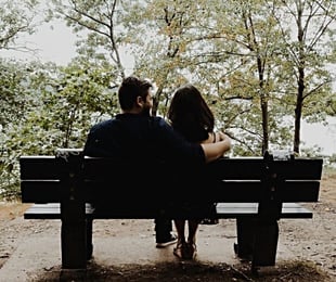 Photo of a man with his arm around a woman on a park bench
