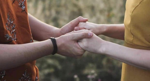 Couple holding hands and facing each other.