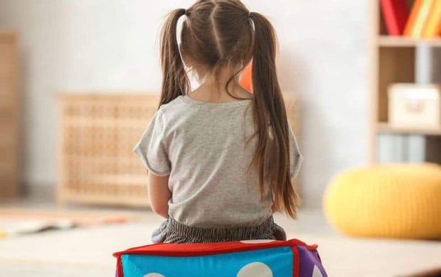 Stock image of a little girl with pigtails sitting with her back to the camera 