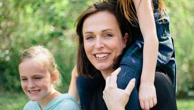 Stock photo of a mom smiling with her two young daughters 