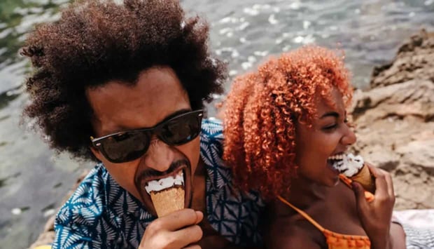 Photo of Black couple eating ice cream together and laughing 