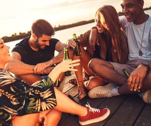 Stock photo of two men and two women laughing and smiling together while drinking on a pier Stock photo of two men and two women laughing and smiling together while drinking on a pier