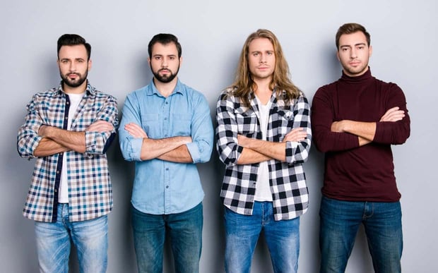 Stock photo of four men with serious expressions standing in a row and crossing their arms 