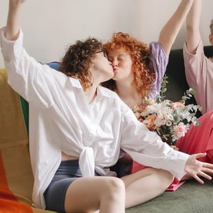 Photo of two young people simultaneously kissing and smiling 