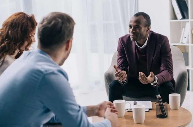 Photo of a couples counselor smiling while talking to a young couple