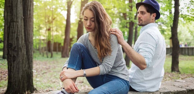 Man resting hand on dejected woman's shoulder Man resting hand on dejected woman's shoulder