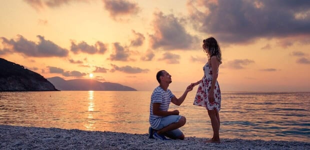 Man proposing to woman on beach at sunset