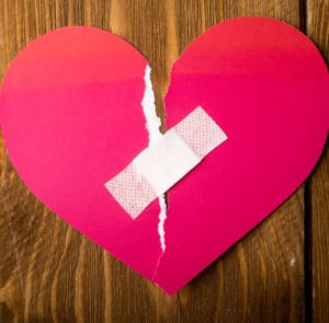 Photo of a ripped paper heart with a Band-Aid over it